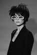 © SHOTPRIME STUDIO - Black and white portrait of a woman with short hair and white sunglasses wearing a dark jacket with a neutral expression