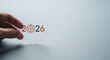 © ABC - Hand holding a transparent disc with the year 2026 and a target symbol representing goals and future planning on a white background