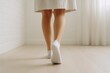 © diproduction - Close-up of a person walking indoors in white socks, showing legs from behind on a light wooden floor in soft natural light environment. Ai generative