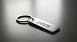 © A B I G A I L - A silver key chain with the year 2026 engraved on it sits on a reflective surface, softly lit. The focus is sharp