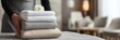 © Eve - Housekeeper placing a fresh stack of clean white and beige towels with a flower on a hotel bed. Hospitality, luxury service, and room cleaning concept, horizontal banner.