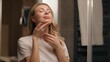 © Yuliia - Gorgeous Caucasian woman young model applying lotion cream serum on neck antiaging beauty routine at bathroom face skincare moisturizing healthy female girl touching skin cosmetic massage at home bath