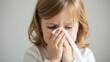 © Fotograf - A young girl blows her nose with a tissue, a common everyday scene