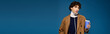 © LIGHTFIELD STUDIOS - Stylish young man holding a coffee cup in a trendy outfit against a blue background
