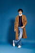 © LIGHTFIELD STUDIOS - Stylish young man showcases contemporary fashion against a blue backdrop