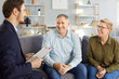 © Studio Romantic - Friendly male financial advisor or realtor meeting with senior couple sitting on sofa. Happy smiling pensioners discussing investment options and life insurance decisions during consultation at home.