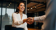 © mamo studios - Happy business woman shaking hands with a client or partner in a modern office, representing agreement, partnership, and successful collaboration.