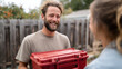 © Sergey - Friendly neighborly exchange: man handing toolbox over fence