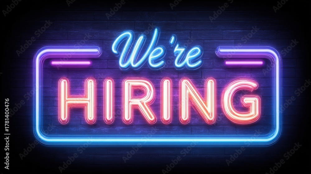 A colorful neon sign displays the message Were Hiring in bold letters against a dark background, capturing attention with its bright lights. This sign encourages job seekers.