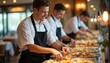 © Pete - Restaurant staff in uniform arrange food on serving trays for a buffet. Chefs and waiters prepare meals in a commercial kitchen, offering catering service. Teamwork in culinary arts.