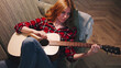 © Марина - Red-haired Woman playing acoustic guitar in cozy living room with warm lighting and relaxed atmosphere during evening hours