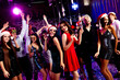 © deagreez - Fun Christmas party crowd dancing in nightclub with festive outfits and smiles at a holiday celebration
