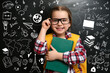 © New Africa - Cute little child in glasses near black chalkboard with drawings