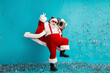 © deagreez - Santa dances with a boombox as confetti falls in blue studio celebrating Christmas and the holiday season fun energy Christmas dream