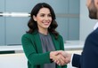 © Meow Creations - Smiling professional woman in green jacket shaking hands with a man in an office