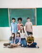 © paulaphoto - Portrait of teacher and group of multicultural students sit in classroom, asian caucasian children together in school. Home school education, diversity multicultural community. Back to school