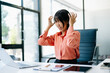© Nuttapong punna - Stressed Asian Businesswoman Feeling Overworked at office desk with laptop.