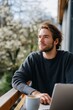© Iryna - Young caucasian male relaxing outdoors with coffee and laptop in springtime