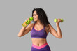 © Pixel-Shot - Sporty young African-American female coach with dumbbell and water bottle on white background
