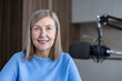 © Liubomir - Senior woman hosts an online radio podcast, creating engaging content and sharing her voice with an audience, embracing modern communication technology with a warm smile