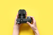 © Pixel-Shot - Female hands with modern professional photo camera on yellow background