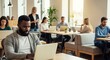 © Patrick Louvet - Focused young man working on laptop in modern cafe with colleagues in a collaborative environment