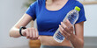 © Natee Meepian - Fitness and Wellness. Young woman tracking hydration while exercising at home.