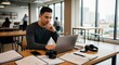© Patrick Louvet - Focused young man working on laptop in modern office setting with notebooks and headphones