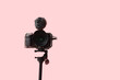 © Pixel-Shot - Professional camera on tripod against pink background, closeup
