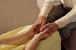 © AnnaStills - Senior Caucasian man gently holding hands of young adult Caucasian woman, showing intergenerational connection and support, close up of hands emphasizing age difference and tenderness