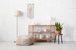 © Pixel-Shot - Wooden shelving unit with lamps and soft pouf in modern room