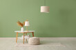 © Pixel-Shot - Table with soft pouf and stylish lamps near green wall in modern room