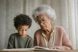 © misunderst00d - Elderly Black woman helping grandson with homework, both focused on open workbook at small vintage kitchen