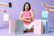 © Pixel-Shot - Beautiful young Asian woman with shopping bags and hands holding payment terminal and money on lilac background