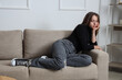 © Pixel-Shot - Sad young woman sitting on sofa at home