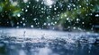 © vectcore - Raindrops falling into a puddle, creating ripples and splashes on the surface with blurred green foliage in the background