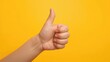 © MetaPixel - Children's hands making a thumbs up gesture against a bright yellow backdrop, creative background for text and layout