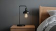 © Giovanni - Closeup of a modern black metal Edison bulb lamp on a wooden nightstand, enhancing the contemporary bedroom's aesthetic, lighting design