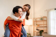 © snowing12 - Asian adult couple playfully piggybacking enjoying happy intimate moments together home living room