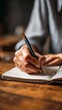 © Oleksandr - A close-up image capturing the delicate motion of a hand writing in a notebook with a pen, showcasing the beauty of creativity and inspiration in a cozy setting.
