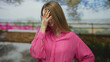 © Krakenimages.com - Woman outdoors in pink shirt expressing frustration with hand on face in a sunny bright garden setting