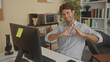 © Krakenimages.com - Man at computer typing with hands forming a heart gesture in a building office workspace; warmth connection.