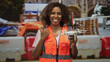 © Krakenimages.com - Woman technician holding drone with thumb pointing to side at building site; confidence and innovation.