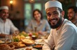 © miss irine - Muslim man in white traditional clothing smiles at Ramadan dinner table. Family gathers around festive meal with various dishes on table. People enjoy food and company in warm atmosphere.