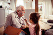 © Davor - Senior grandfather laughing while child granddaughter paints his face at home