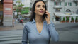 © Krakenimages.com - Woman talking on phone outdoors in urban street setting, expressing emotion against city backdrop, wearing blue, young hispanic female on sidewalk engaged in conversation