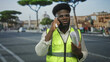 © Krakenimages.com - Man in high visibility vest holds phone to ear and grips rolled plans on street; urban work determination.