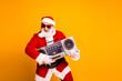 © deagreez - Santa in a red costume with a retro boombox poses against a bright orange background for festive holiday music fun lighthearted Christmas vibe