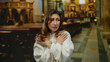 © Krakenimages.com - Young woman in a church interior appears fearful clutching arms with a worried expression symbolizing anxiety and emotion surrounded by religious motifs creating a dramatic atmosphere.