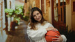 © Krakenimages.com - Woman smiling holding basketball on a vibrant urban street with warm sunlight filtering through buildings in a cityscape scene showcasing youthful energy and outdoor activity.